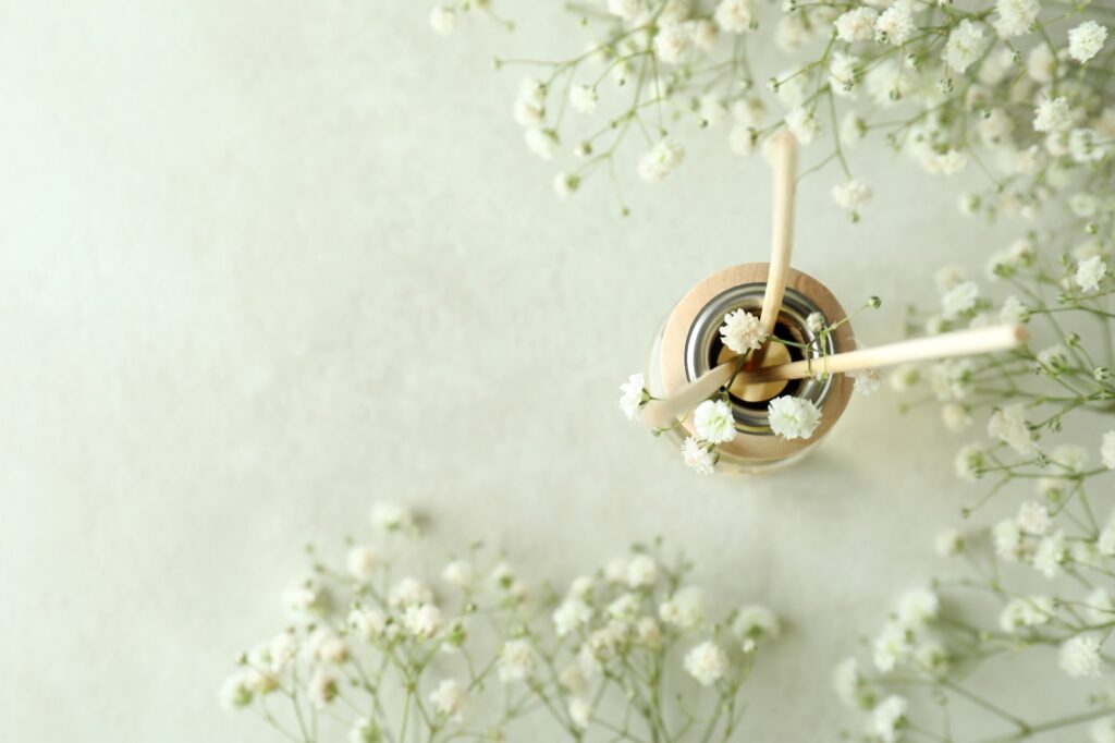 Diffuser and flowers on white textured table