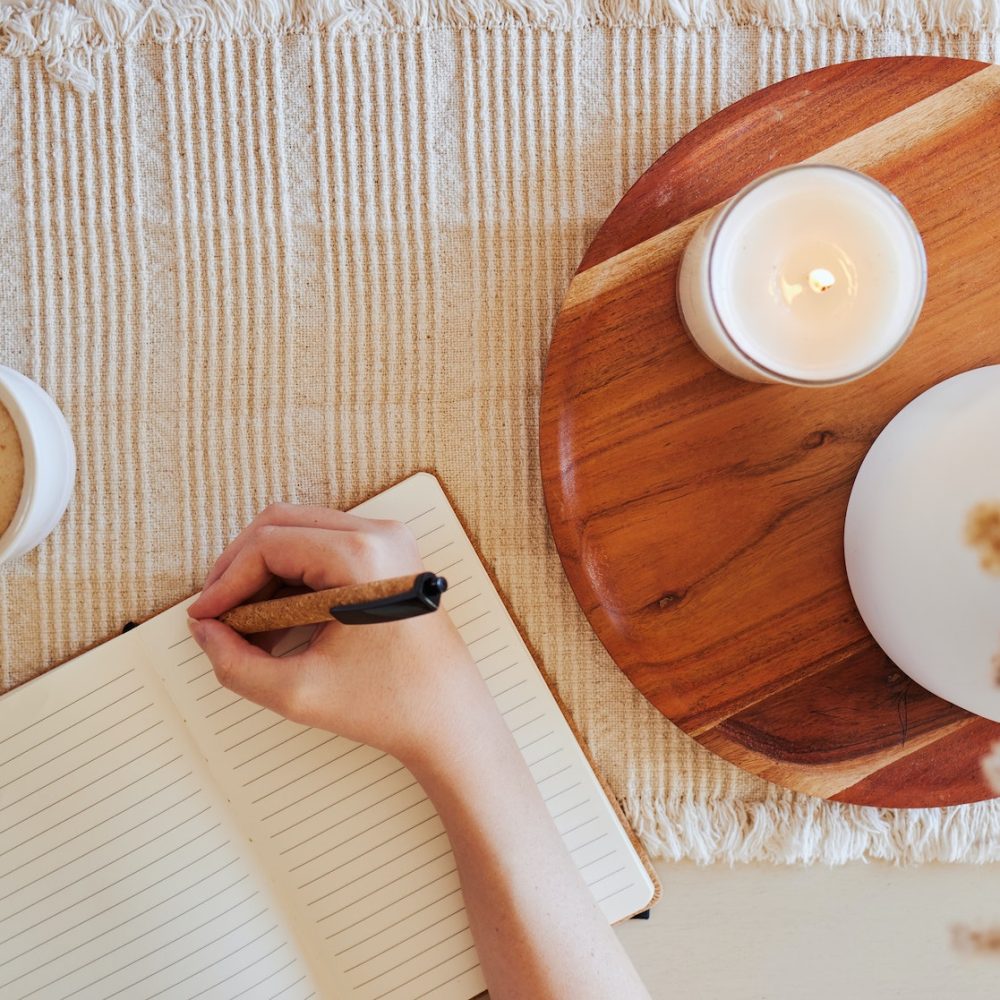 Coffee, hand and writing in journal top view with candle for calm, peace and relax morning routine.